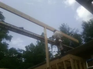 Carpenter setting a ridge beam over a new addition frame — Ice Dam Removal by Roofing Brothers in Pinehurst