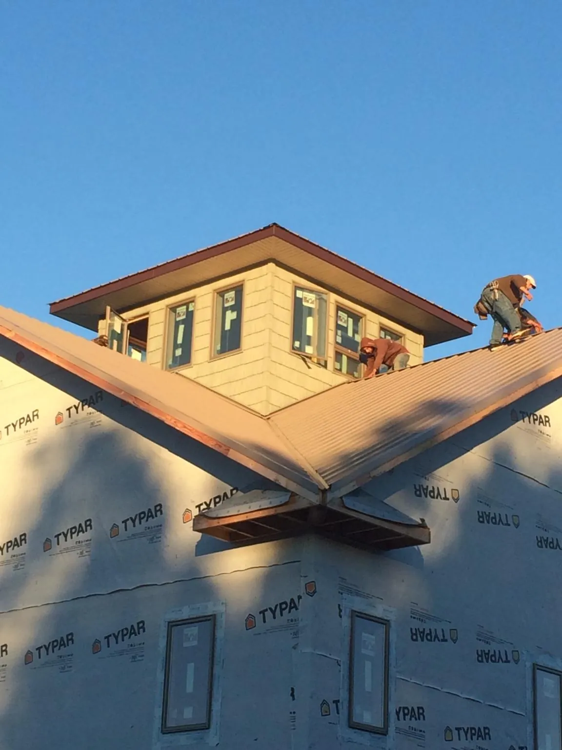Roofers working around a rooftop cupola on a new metal roof at sunset — Roof Waterproofing in Pinehurst by Roofing Brothers